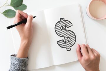 Dollar symbol drawn in black on a blank notepad